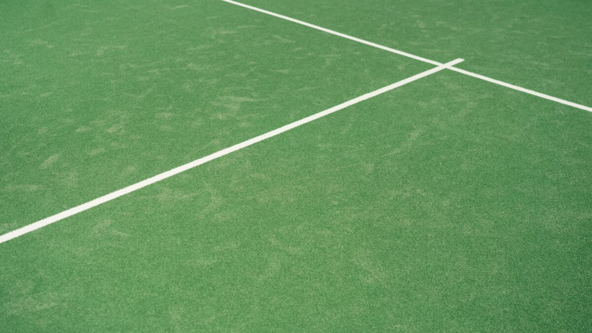 Close-up view of tennis court's vibrant green surface with white lines