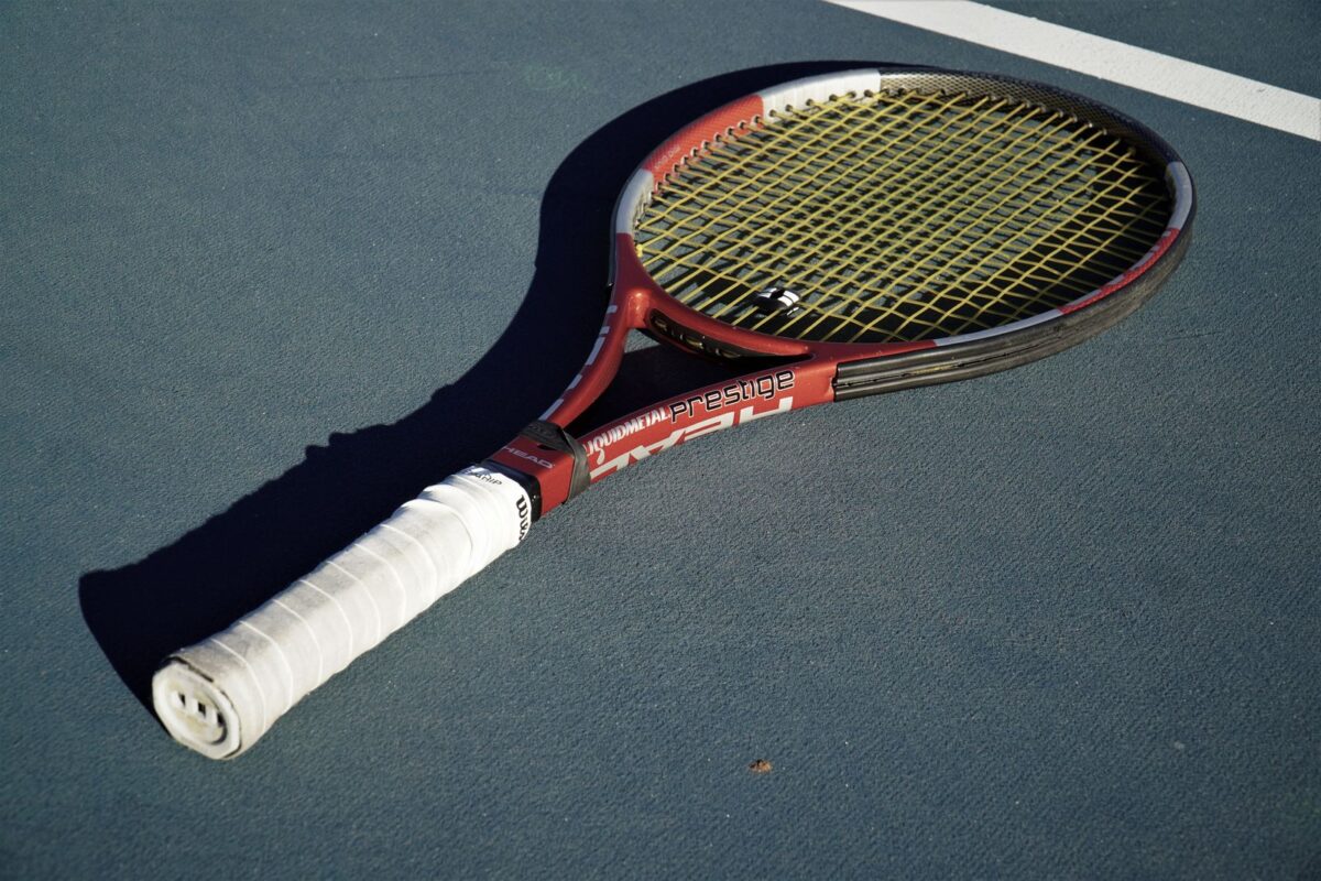 Raquette de tennis posée sur un court en dur bleu, surface de la tournée américaine