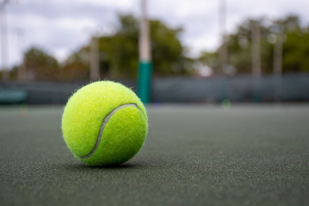 Vibrant tennis ball on outdoor court surface, focusing on texture and color.